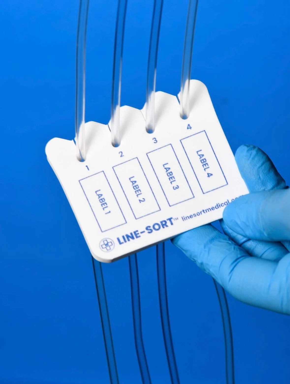 A gloved hand holds the four-channel Line-Sort pad on IV tubing